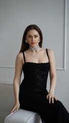 Fototapeta premium Elegant woman in a black lace dress, showcasing intricate jewelry and poised posture, embodies timeless beauty and sophistication.