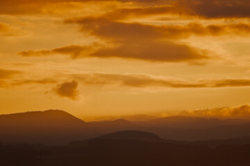 Fototapeta premium Warm Golden Sunset Over Dark Mountain Silhouettes