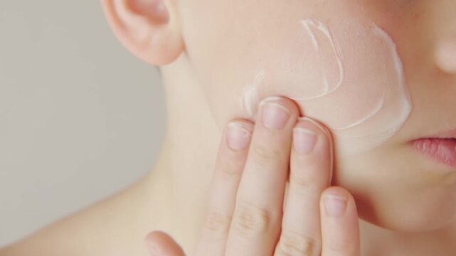teenage boy applying acne cream, Teen boy focused on facial skincare, highlighting self-image issues and teenage skin concerns
