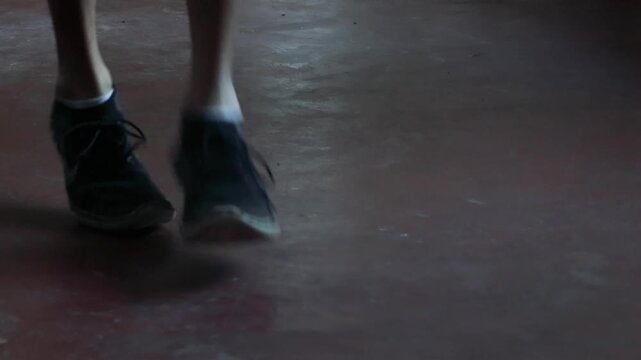 Athlete feet skipping rope in a dark moody industrial gym cardio workout motivation