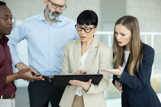 Diverse business colleagues analyzing data on a tablet, showing confusion and concern over a problem discovered during a meeting