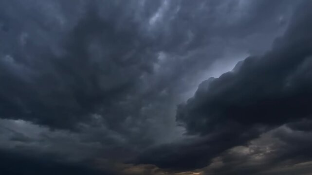 Slow motion aerial pan and tilt of storm clouds with lightning flashing over open horizon and rolling cumulonimbus sky at evening