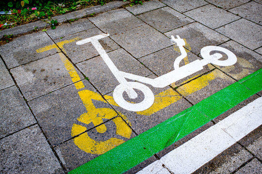 Parking space marked for electric scooters on a sidewalk in a busy urban area during daylight hours