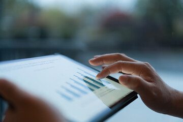 Close-up of hands holding a tablet displaying data charts for analysis © zhu difeng