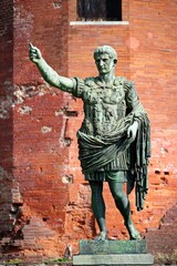 The bronze statue of Cesare Augusto against the backdrop of the ancient red Porta Palatina, Torino, Piemonte, Italy.
