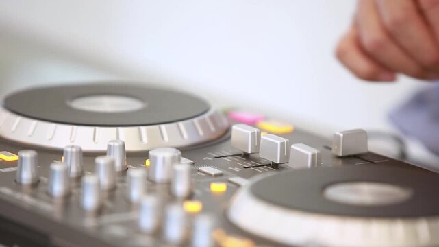 Hand of DJ adjusting knobs and sliders on audio mixer controller