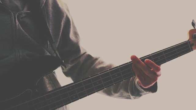 Strumming electric guitar. Musician plays music. Man fingers holding mediator. Man hand playing guitar neck in dark room