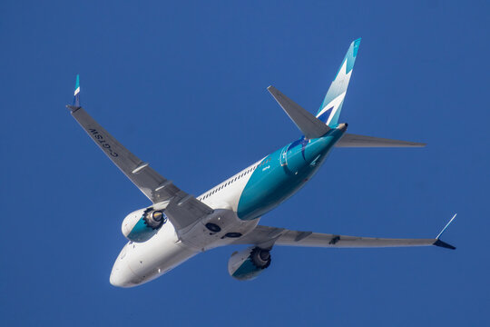 Calgary, Alberta, Canada. March 16, 2026. A WestJet Boeing 737 MAX 8 aircraft with registration C-GTSW soaring through a clear blue sky.