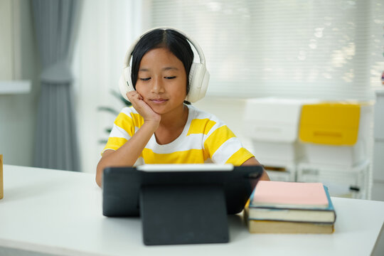 Asian girl with headphones enjoying online class on digital tablet