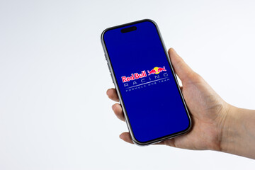 Fototapeta premium Moscow, Russia, March 14, 2026: Smartphone in hand showing Red Bull Racing Formula 1 Team logo on display, isolated on white background. Team spirit, racing heritage and podium ambitions in F1