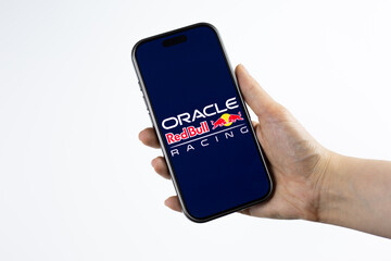 Fototapeta premium Moscow, Russia, March 14, 2026: Hand holding smartphone displaying Oracle Red Bull Racing logo on screen, white background. Visual representing AI powered strategy and technology in motorsport