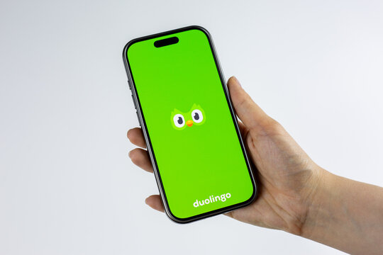 Moscow, Russia, March 14, 2026: Hand holding smartphone displaying green Duolingo owl logo on screen, isolated. New language course addition and educational content update on platform