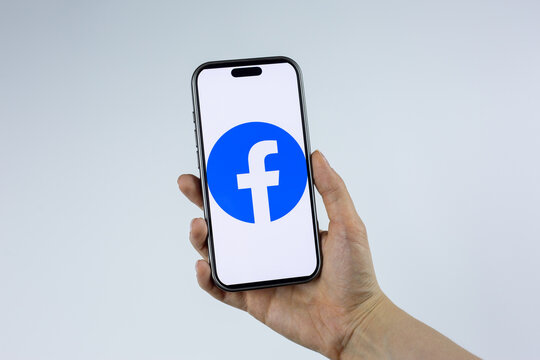 Moscow, Russia, March 14, 2026: Female hand holding a smartphone displaying the new round Facebook corporate logo on screen, isolated on white background. Meta company branding visual