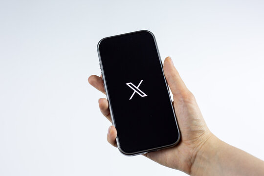 Moscow, Russia, March 14, 2026: Smartphone in a female hand showing the X logo on display, isolated on white background. Editorial image for X platform as news source and long form content hub