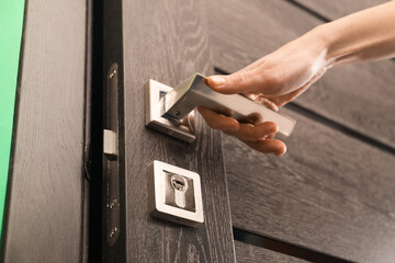 Obraz premium Woman opening wooden door with key indoors, closeup