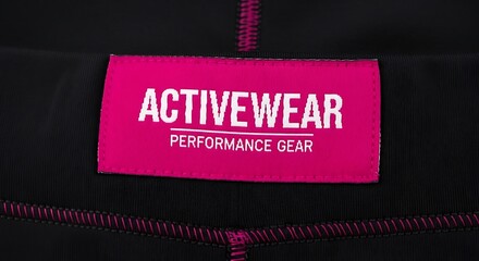 Close-up of black activewear pants with a pink tag; text reads 