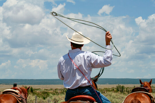 Galisteo, New Mexico. Cowboy on horseback with lasso in the air at a ranch 