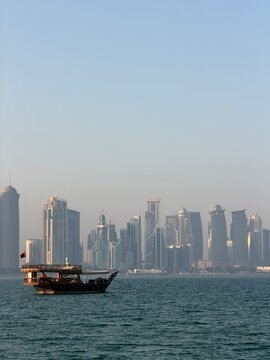 Traditional dhow boat with Doha skyline in West Bay Qatar.
Traditional wooden dhow boat sailing in the Persian Gulf with Doha skyline in the background.