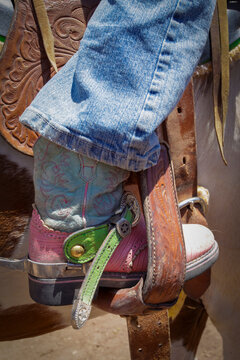 Young cowgirl boot with spur in stirrup, western riding detail