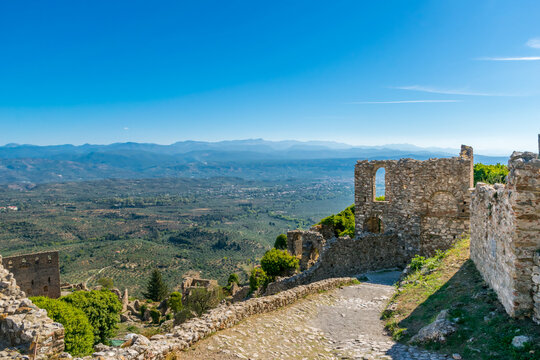 Sunny panoramic view of remains of Mystras fortified town with Sparta below in the valley, Laconia, Greece