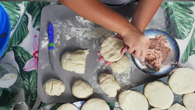 A woman spreads minced meat on freshly kneaded dough. High quality 4k footage