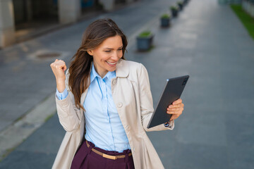 Fototapeta premium Businesswoman celebrating success after reading good news on tablet