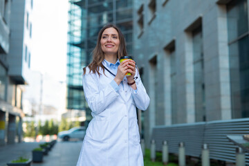 Fototapeta premium Female doctor enjoying coffee on urban street