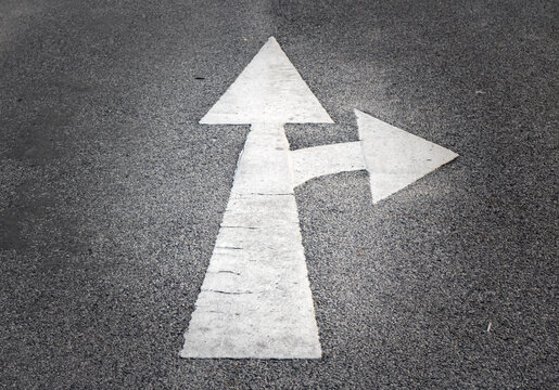 White straight and right turn arrow road marking painted on asphalt street surface, traffic direction symbol used for transportation guidance and navigation.