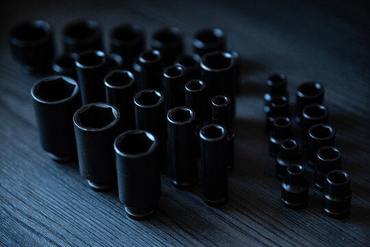 Deep black impact sockets stand in the foreground with sharp clarity, showcasing their hexagonal openings and robust industrial construction. 