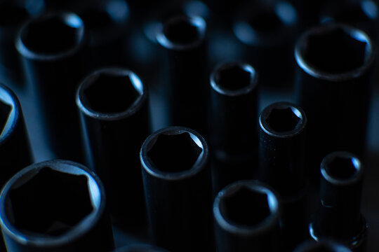 A cluster of black impact sockets is captured from a top-down perspective, with the central row in sharp, crisp focus to showcase the precision-engineered hexagonal heads. 