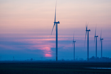 Wiatraki elektryczne na tle zachodzącego słońca. © Monika