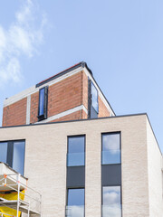 Obraz premium Diepenbeek, Belgium. Modern residential building under construction with exposed brick structure and scaffolding