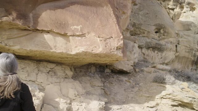 Woman Viewing Native American Rock Art on Sandstone Cliff Wall