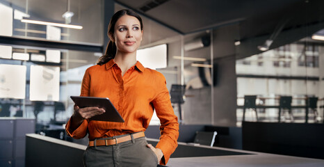 Businesswoman CEO using fintech tab app standing at workplace in office. Latin Hispanic mature...