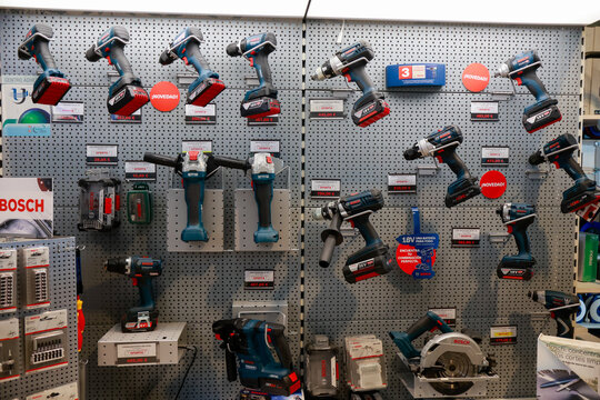 Pamplona, ​​Spain - February 28, 2026. Cordless electric drills in a tool shop. The drills are hanging on a metal pegboard, lined up in a row. They are dark blue with black and red details,Bosch brand