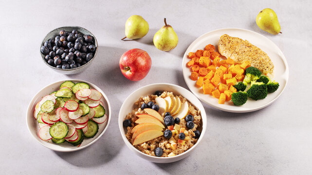 Balanced low histamine meal set with chicken, sweet potato, broccoli, cucumber radish salad and oatmeal with fruit and blueberries, heart healthy, diabetes and blood pressure friendly diet concept.