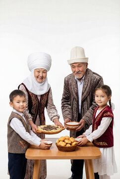 Kazakh family with grandparents and children presenting traditional food and drinks