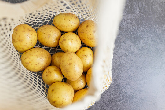 Fresh yellow potatoes filling an eco friendly net bag ready for cooking or storage at home