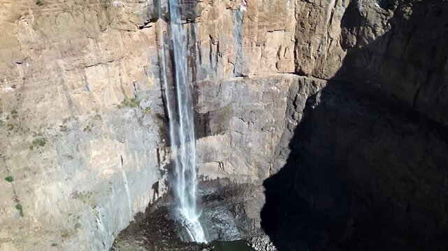 Aerial drone view of Maletsunyane Falls in Lesotho, a powerful waterfall plunging down a high sandstone cliff with a rainbow forming in the mist below