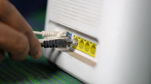 Close Up of Office Employee Plugging Ethernet LAN Cable into Wifi Router.  Technician Connecting RJ45 Network Cable to High Speed Modem. 