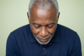 Obraz premium Elderly African American man in polo shirt looking thoughtful