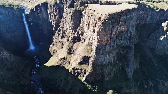 Aerial drone view of steep canyon cliffs surrounding Maletsunyane Falls in Lesotho, highlighting the dramatic rock formations and deep valley below