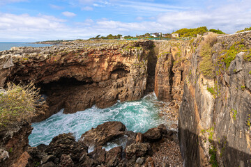 The turquoise waters of the Atlantic Ocean rush under limestone cliffs at the Boca do Inferno Mouth of Hell, a seaside cave in Cascais, Portugal. © Kirk Fisher