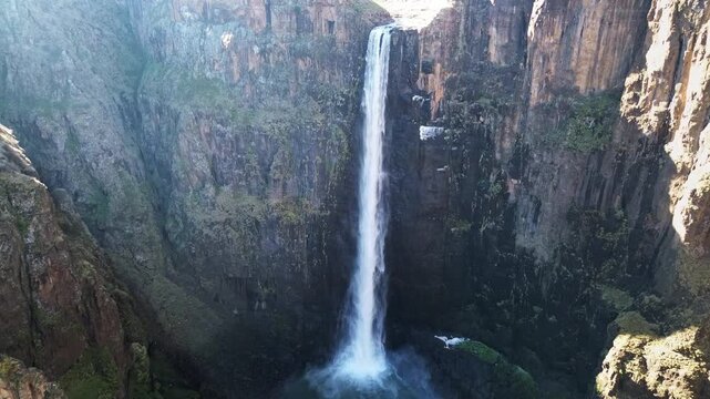 Aerial drone view of Maletsunyane Falls dropping into a deep canyon in the Lesotho highlands, surrounded by rugged cliffs and vast mountain landscapes