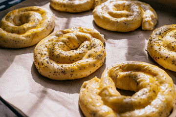 Naklejka premium Unbaked spiral Moldovan placinte on baking tray with poppy seeds in sunlight