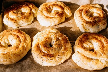 Six freshly baked golden spiral Moldovan placinte on baking tray overhead