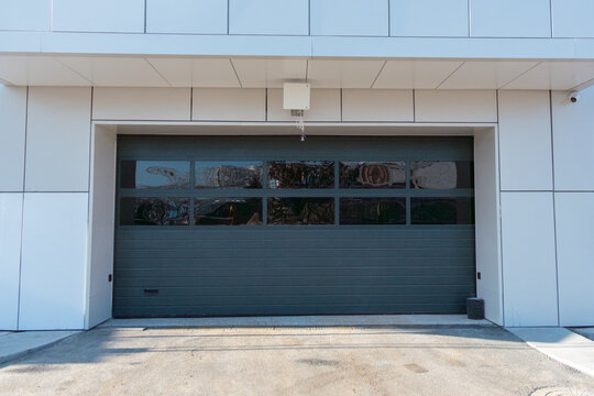 Modern commercial garage door with large glass panels and sleek design, situated in a contemporary building with clean lines and minimalistic architecture