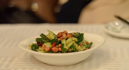 Cucumber salad with peanuts in a white bowl