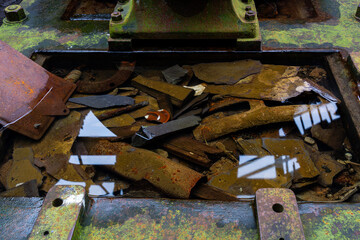 Rusted iron machinery and slate fragments submerged in a shallow pool of water inside a derelict industrial structure