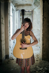 Obraz premium Sensual Female Musician Holding Acoustic Guitar in Abandoned Interior
